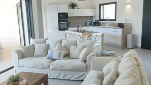 Uma sala de estar moderna com sofá, mesa de centro e área de refeições com cadeiras.