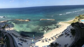 Ein Strand mit klarem Wasser, einem steinernen Wellenbrecher und einer Reihe von Liegestühlen.