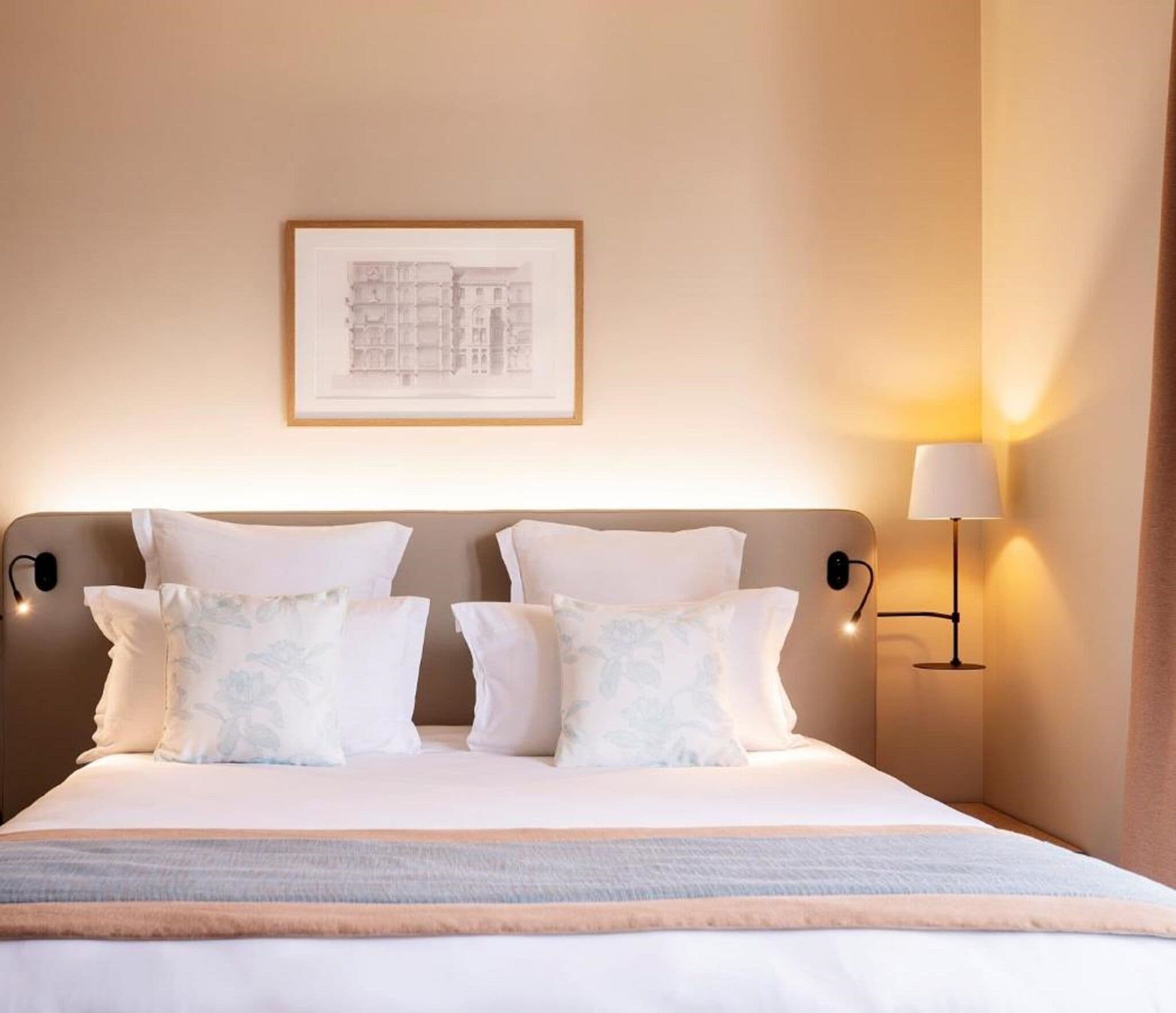 Une chambre d’hôtel avec un lit, des oreillers, un tableau encadré au mur et une lampe de chevet.