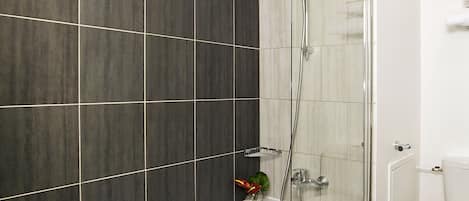 A modern bathroom with a bathtub, shower, and toilet.