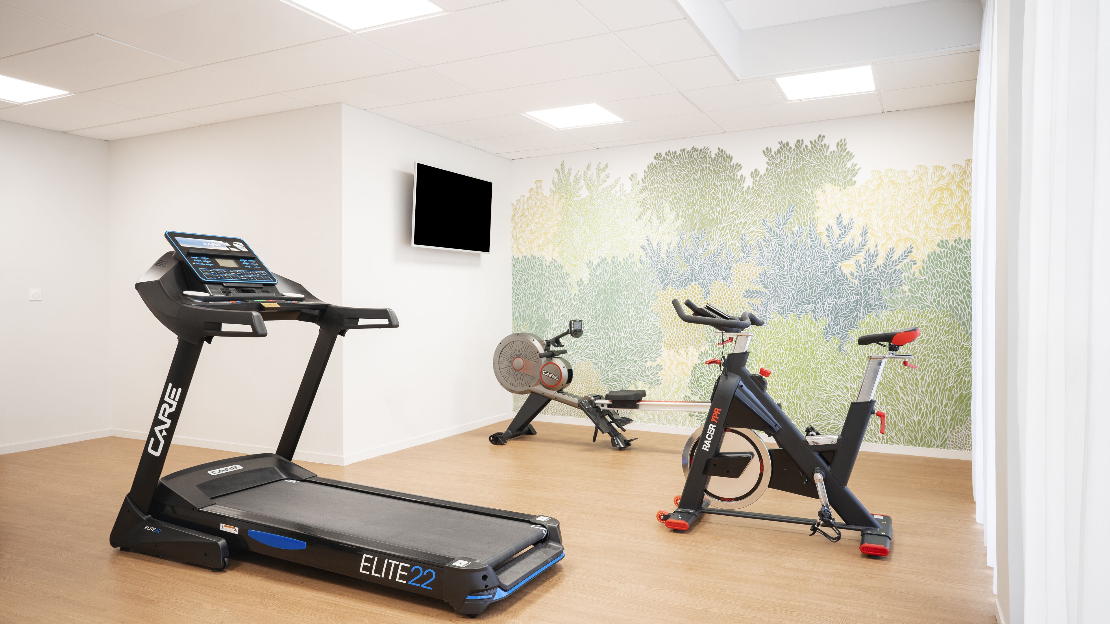 Un gimnasio con cinta de correr, máquina elíptica y bicicleta estática.
