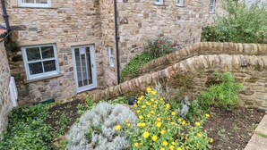 A stone building with multiple windows and a garden with yellow flowers. - Brancepeth (Bishop Auckland)