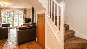 A living room with a sofa, a television, and a fireplace. There is a staircase with a wooden door and a view of the outdoors. - Brancepeth (Bishop Auckland)