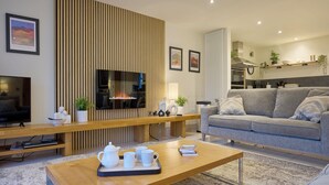 Un salon moderne avec un téléviseur, un canapé, une table basse et une cheminée.