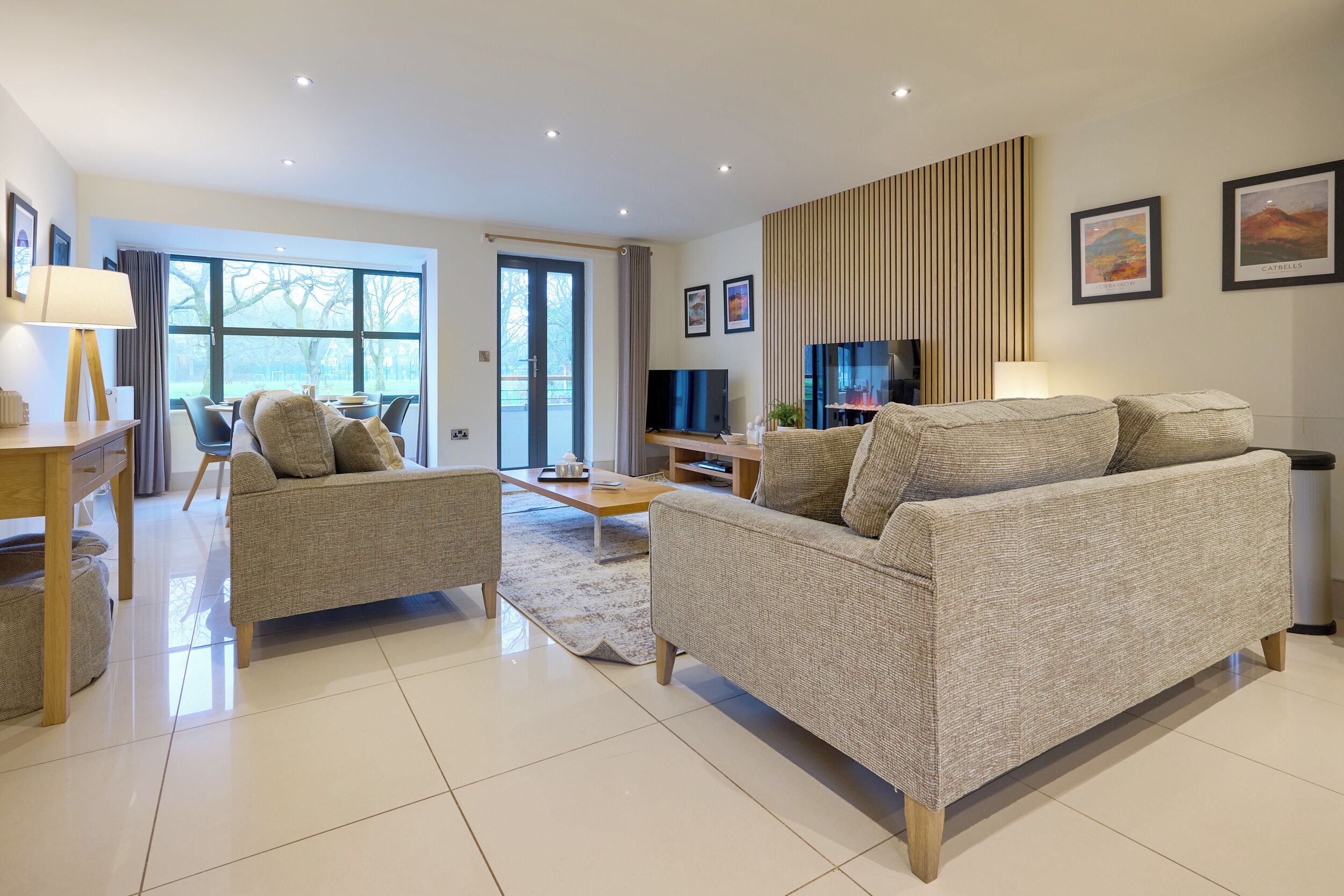 A modern living room with a sofa, armchairs, a coffee table, and a TV.