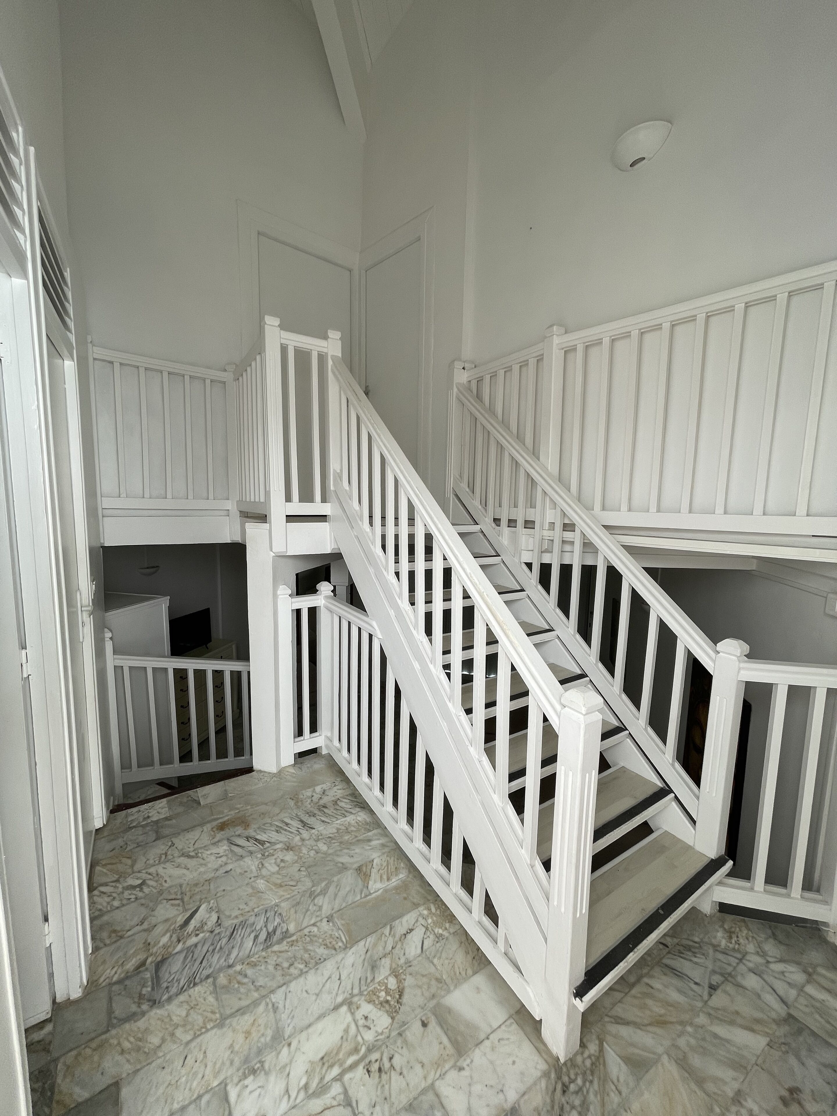 A white staircase with marble steps and white railings.