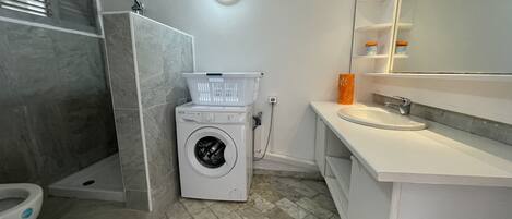 A modern bathroom with a washing machine, a toilet, and a sink.
