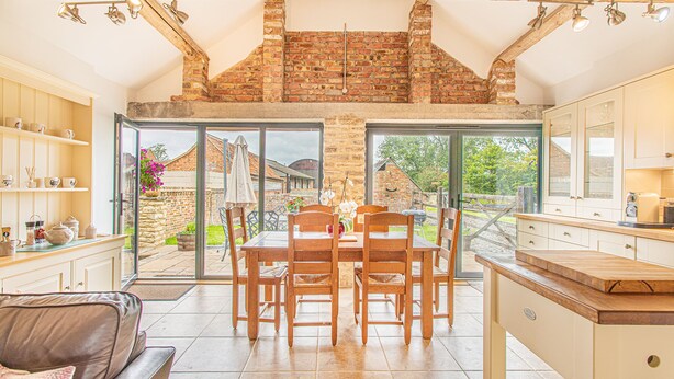 A spacious kitchen with a dining area, large windows, and a view of the garden. - Countryside Retreat/Panoramic Picturesque Views (Chippenham)