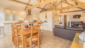 A spacious kitchen with wooden beams, a dining area with a wooden table and chairs, and a living room with a leather sofa. - Countryside Retreat/Panoramic Picturesque Views (Chippenham)