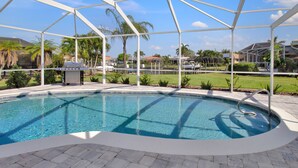 A covered swimming pool with a clear view of the surrounding area, including palm trees and houses.