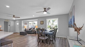 A spacious living area with a dining table, chairs, and a ceiling fan.
