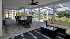 A covered patio with a pool, outdoor furniture, and a view of the surrounding neighborhood.