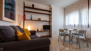 Un soggiorno moderno con un divano, una TV e un tavolo da pranzo per quattro persone.