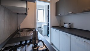 Una cucina moderna con piano cottura a gas, lavello in acciaio inossidabile e mobili bianchi.