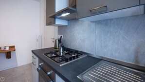 Una cucina moderna con piano cottura a gas, bollitore e cappa aspirante in acciaio inossidabile.