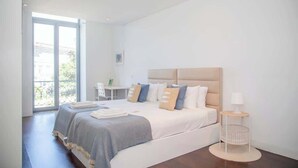 Ein modernes Schlafzimmer mit einem großen Bett, einem Nachttisch und Blick ins Freie.