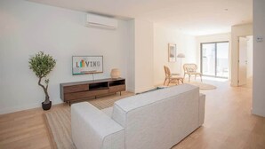 A modern living room with a sofa, a potted plant, a TV, and a minimalist console table. - Liiiving in Porto - City Design Apartment C (Porto)