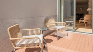 An outdoor patio with wicker furniture and a glass door leading to an interior space. - Liiiving in Porto - City Design Apartment C (Porto)