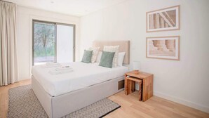 A modern bedroom with a large bed, a small wooden side table, and two framed pictures on the wall. - Liiiving in Porto - City Design Apartment C (Porto)