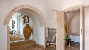 A hallway with a large vase, a chair, and a wooden door. - Stylishly restored trullo with private pool and stunning views (Martina Franca)