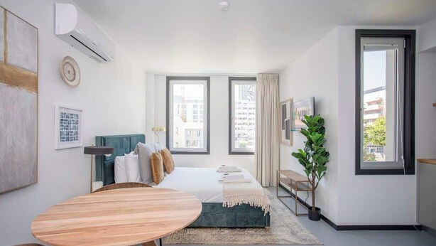 A modern bedroom with a bed, bedside tables, a round wooden table, and a large window. - Liiiving in Porto - City Design Studio II (Porto)