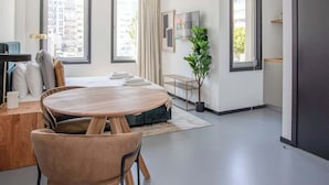 A modern, spacious living area with a round wooden table, a sofa, and a TV mounted on the wall. - Liiiving in Porto - City Design Studio II (Porto)