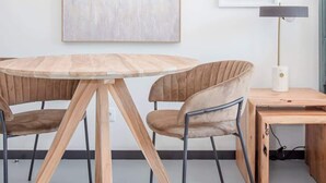 A modern dining area with a round wooden table, two upholstered chairs, a wall-mounted air conditioner, and a framed abstract artwork. - Liiiving in Porto - City Design Studio II (Porto)