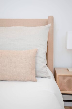 Un lit avec deux oreillers, une tête de lit en bois et une table de chevet avec une lampe.