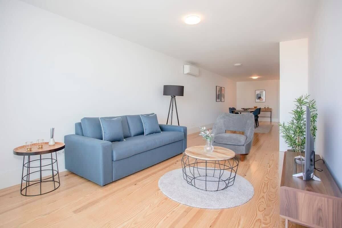 A modern living room with a blue sofa, a round coffee table, and a floor lamp.