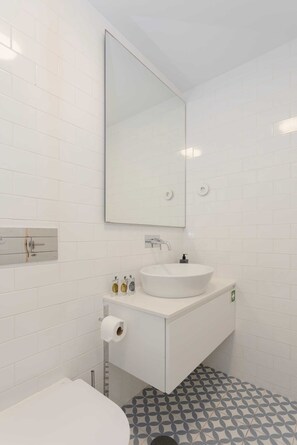 Een moderne badkamer met een witte wastafel, spiegel en toilet.