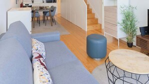 Ein modernes Interieur mit Holzboden, einer Treppe, einer Essecke und einem Wohnbereich mit Sofa und rundem Tisch.