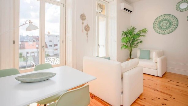 A bright room with a white table, a white sofa, and a potted plant. - Liiiving in Porto - Downtown Balcony Studio (Porto)
