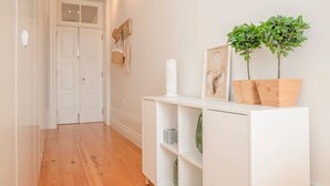 A hallway with a white console table, wooden flooring, and a door at the end. - Liiiving in Porto - Downtown Balcony Studio (Porto)