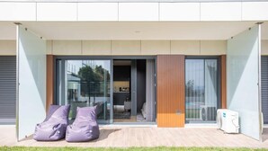 A modern building with a glass entrance, a sliding door, and a patio area with two bean bags. - Liiiving in Porto - Dragão Pool View (Porto)