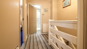 A narrow hallway with a striped carpet, a white railing, and a door leading to another room. - Harry s - 2 Bedroom Holiday Home - Tenby (Tenby)