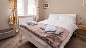 Ein Schlafzimmer mit einem Bett, einem Nachttisch, einem Heizkörper und einem Fenster mit Vorhängen.
