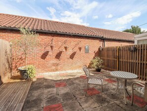 A patio with a brick wall, a wooden fence, and a tiled roof. - 8 Williamson Drive (Ripon)