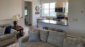 Un salon comprenant un canapé, une lampe et un coin repas avec des chaises et une table.