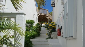 A narrow staircase leading to a wooden balcony, surrounded by white walls and greenery. - 5 min from Orient Bay-magical view (Collectivity of Saint Martin)