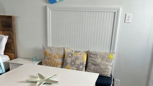 Een kamer met een witte tafel, blauwe stoelen, een zeester decoratie en een bank met kussens.