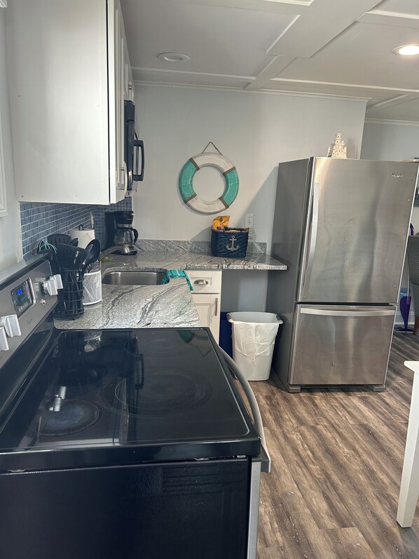 A kitchen with a black stove, stainless steel refrigerator, and a blue basket with an anchor design on the countertop. - Ocean view, fully renovated beach condo!!! Steps to the sand, sleeps 6 (Old Orchard Beach)