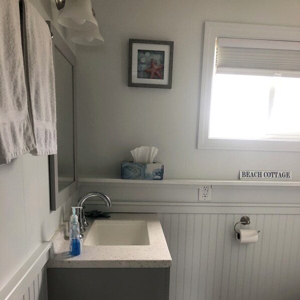 A bathroom with a sink, mirror, towel rack, and a window. - Ocean view, fully renovated beach condo!!! Steps to the sand, sleeps 6 (Old Orchard Beach)