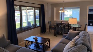 A living room with a sofa, a coffee table, and a dining area with chairs and a table. - “Stay Anchored” Lake Tippecanoe channel front with pier and great lake views (Leesburg)