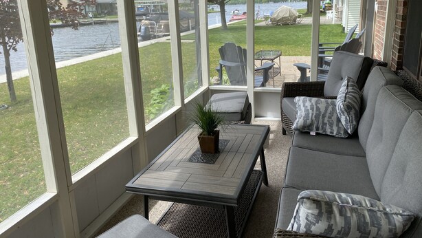 A covered patio with a view of a lake, outdoor furniture, and a table with a plant. - “Stay Anchored” Lake Tippecanoe channel front with pier and great lake views (Leesburg)