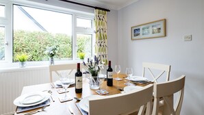 A dining room with a table set for four, featuring wine glasses, plates, and cutlery. - Longhouse Bungalow (Wadebridge)