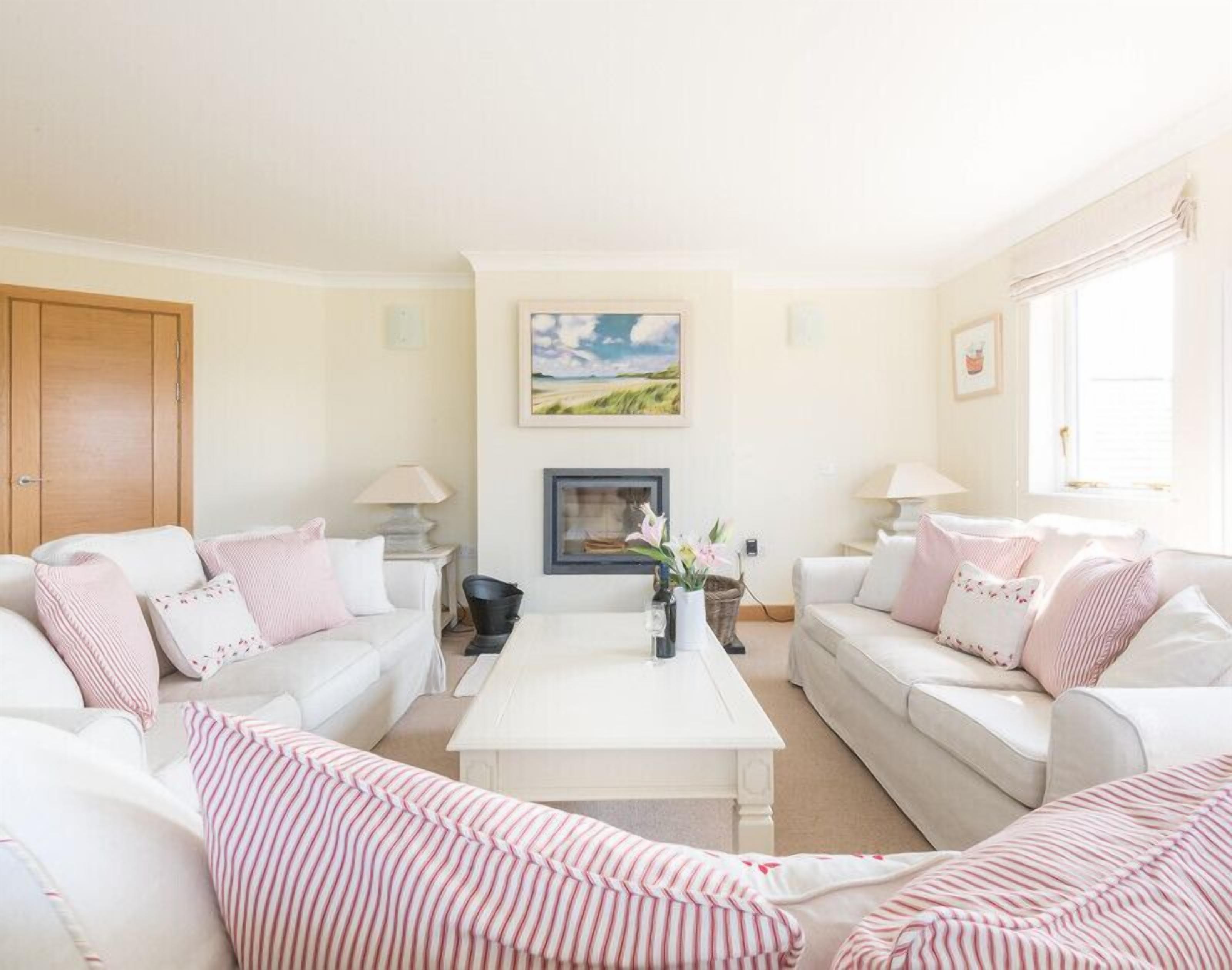 A living room with two white sofas, a white coffee table, and a painting on the wall.