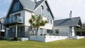 A modern two-story house with a balcony, a covered porch, and a well-maintained lawn.
