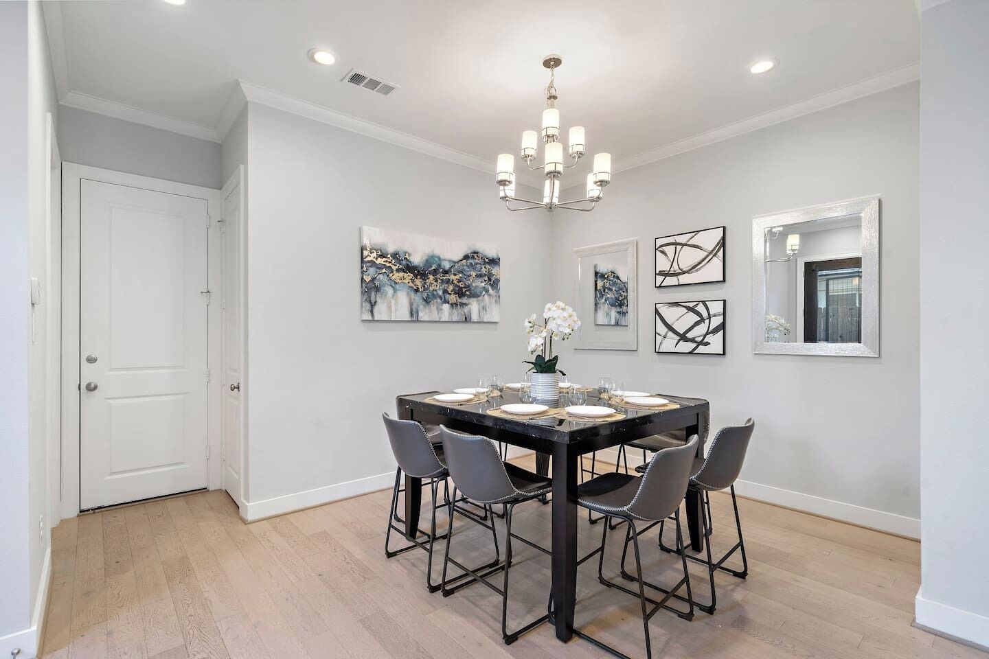 A dining area with a rectangular table, six chairs, and a chandelier.