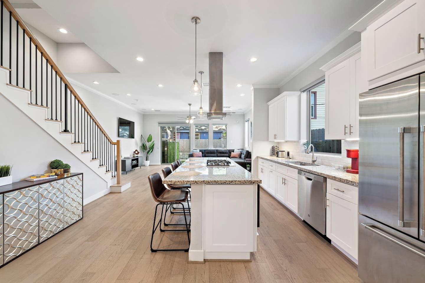 A modern kitchen with a central island, stainless steel appliances, and a staircase leading to another level.