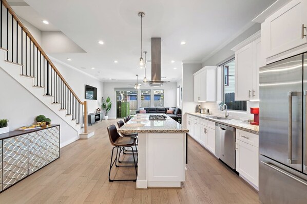 A modern kitchen with a central island, stainless steel appliances, and a staircase leading to another level.
